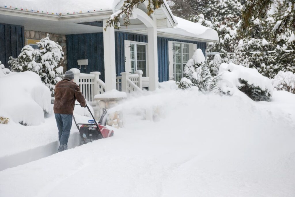 Man snow blowing his driveway.