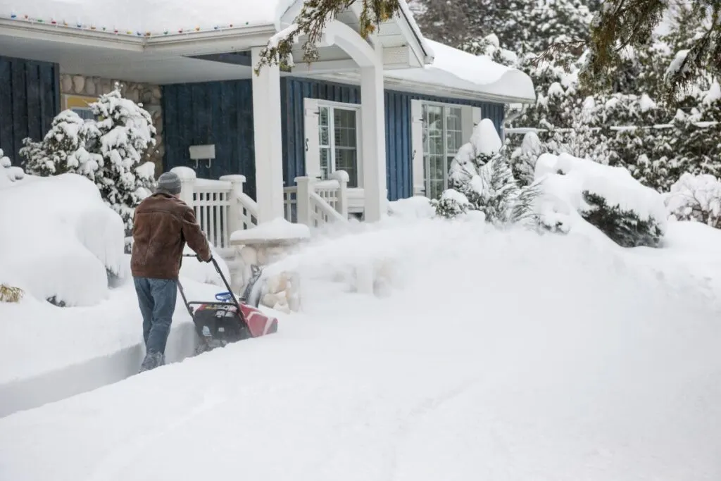 Man snow blowing his driveway.