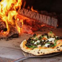 Kale pizza out of fire oven
