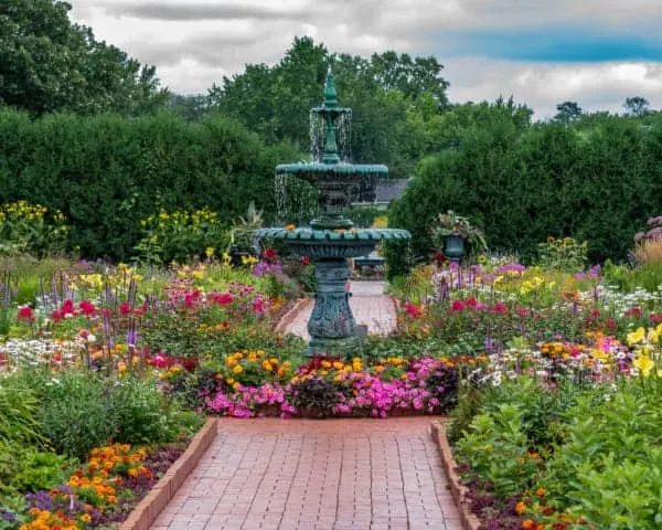 View of a fountain surrounded by flower beds at Clemens Garden in St. Cloud -- one of the best places to visit in Minnesota.