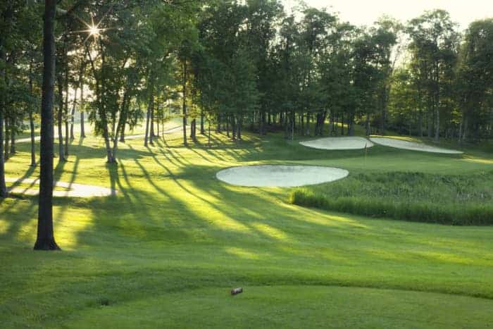 Sun peeking through the trees onto sand traps -- in addition the game, golfers will enjoy beautiful scenery at the best golf courses in Minnesota.