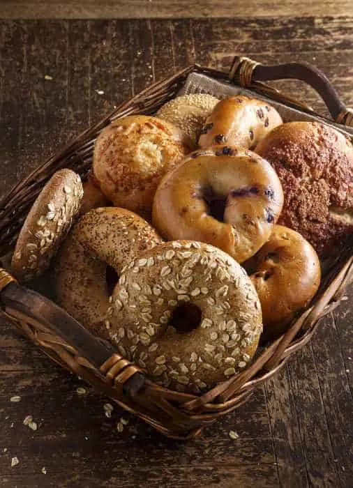 Fresh assorted bagels on a wooden table.