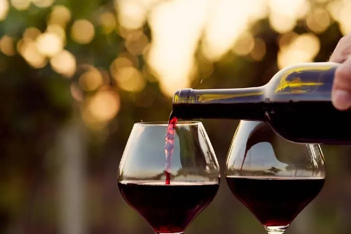 Red wine being poured into two wine glasses.