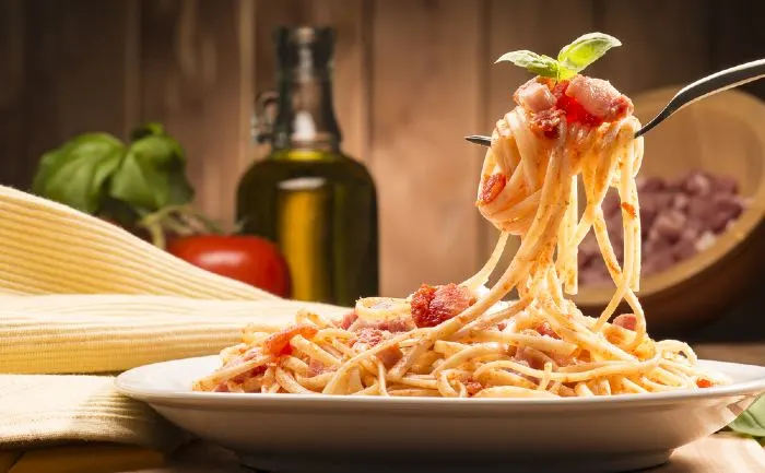 Spaghetti with amatriciana sauce on a wooden table.