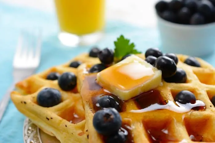 Waffles topped with butter, syrup, and blueberries.