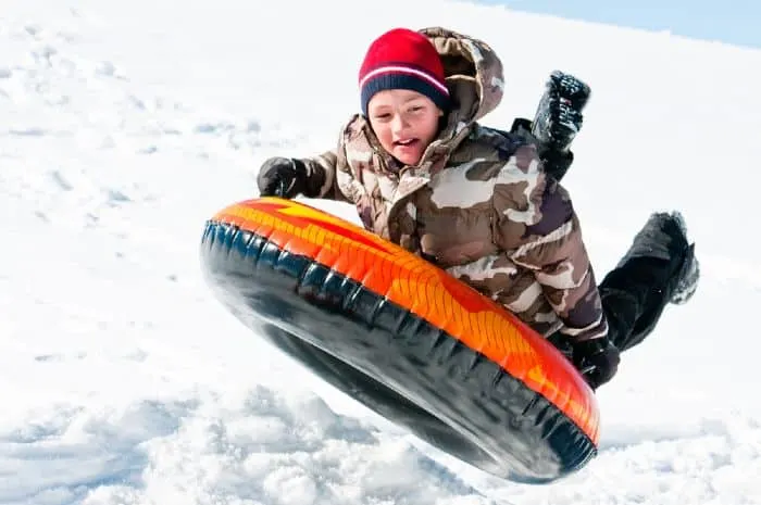Boy riding a tube down a hill covered in snow