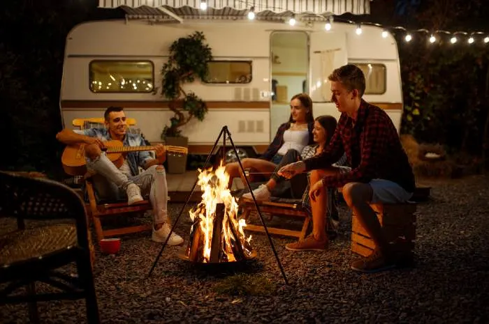 Friends playing on guitar by the campfire, camping
