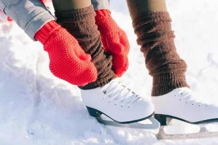 Girl in dress skates mittens tying shoelaces

