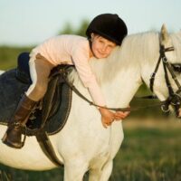 Young girls on white horse in nature