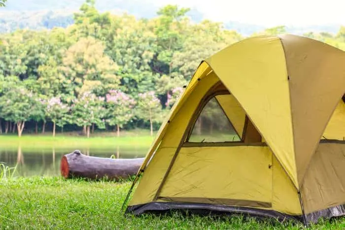 Camping tent and log near water