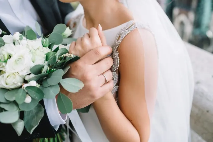 Close-up of groom's hand holding bride's wrist tender

