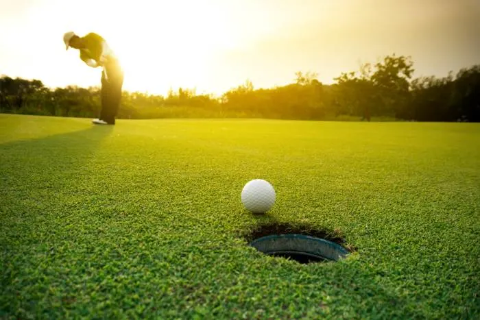 Golfer putting golf ball 