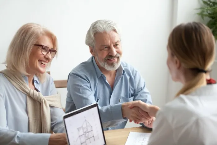 Smiling satisfied senior couple making sale purchase deal 