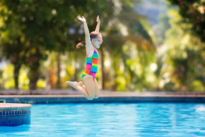 Child jumping and diving in a swimming pool at one of the fun things to do in Fairmont, Minnesota