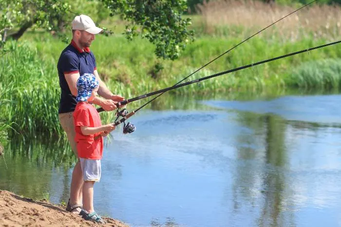 Family fishing. Father and son with fishing rods on lake side

