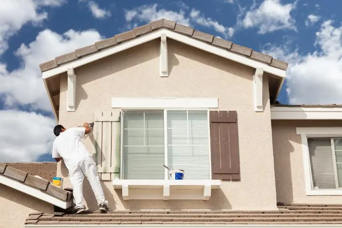 Professional house painter painting the trim and shutters of a home