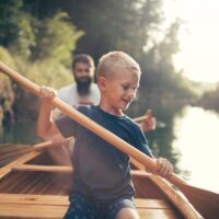 Young boy canoeing on the lake with his father