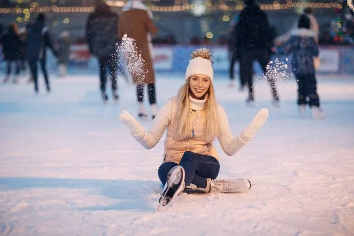 Young smiling woman with skates on the ice rink
