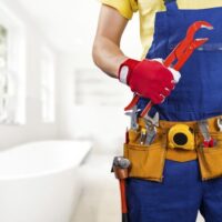 Plumber holding tools in bathroom