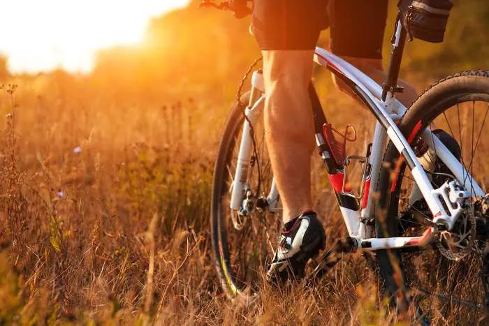 Closeup of cyclist man legs riding mountain bike on an outdoor trail in autumn forest