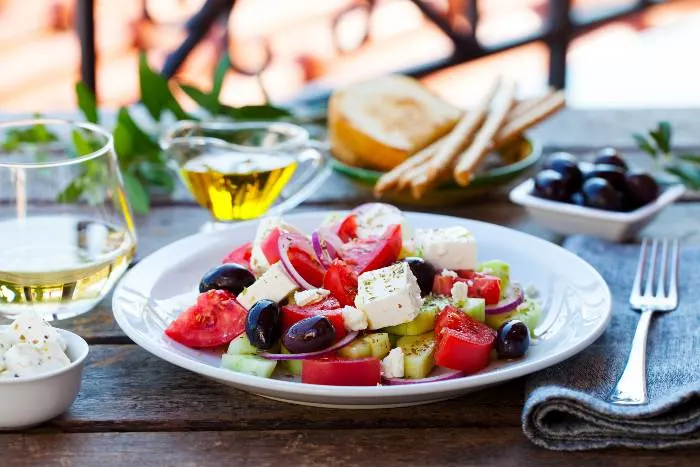 Greek salad. Fresh vegetables, feta cheese, and black olives with white wine.