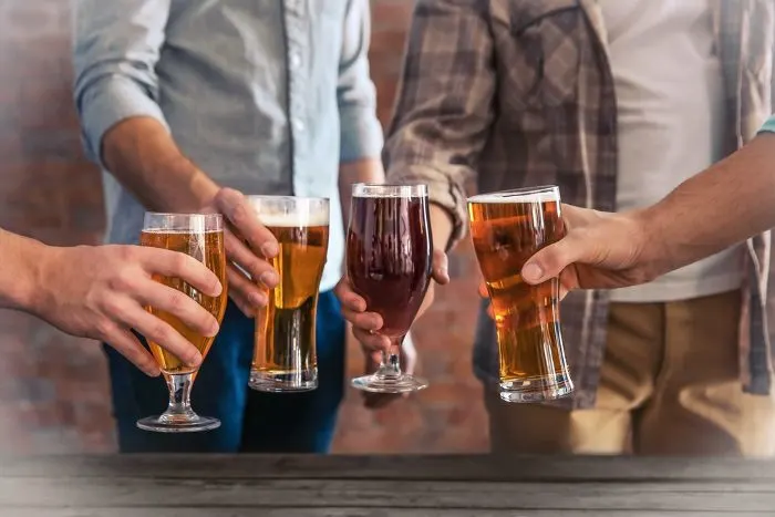 Male group clinking glasses of dark and light beer at the table
