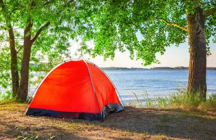 Red tourist tent on the lake in summer