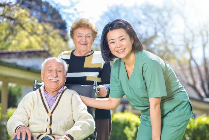 Senior couple in the garden with their caregiver
