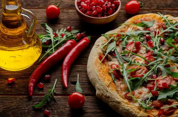 Vegan pizza with fresh garnet and arugula leaves