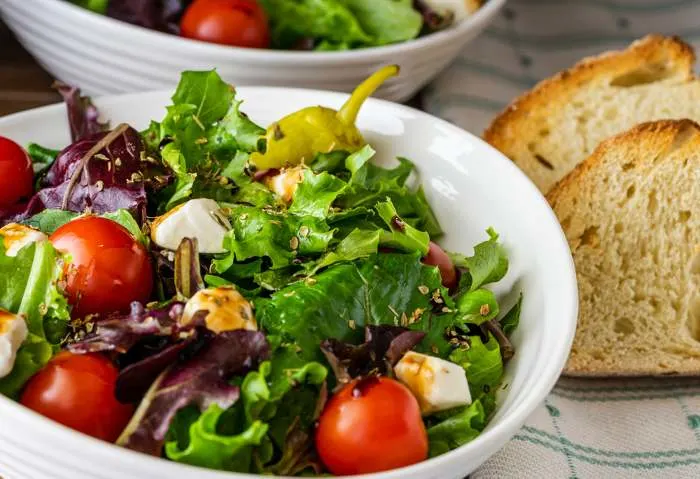 Bowl of salad greens, grape tomatoes and mozzarella pearls.