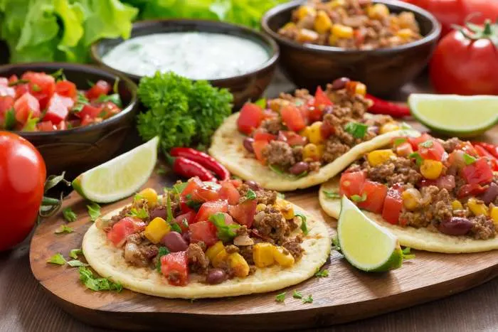 Mexican cuisine - tortillas with chili con carne and tomato salsa on a wooden board