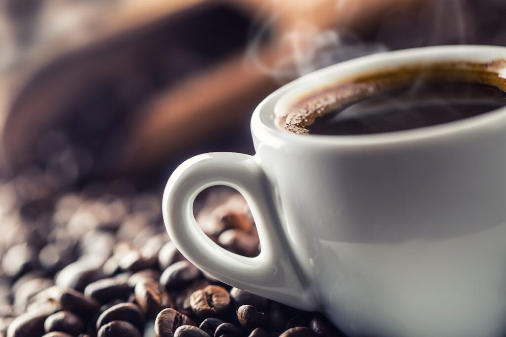 Cup of black coffee with beans on wooden table
