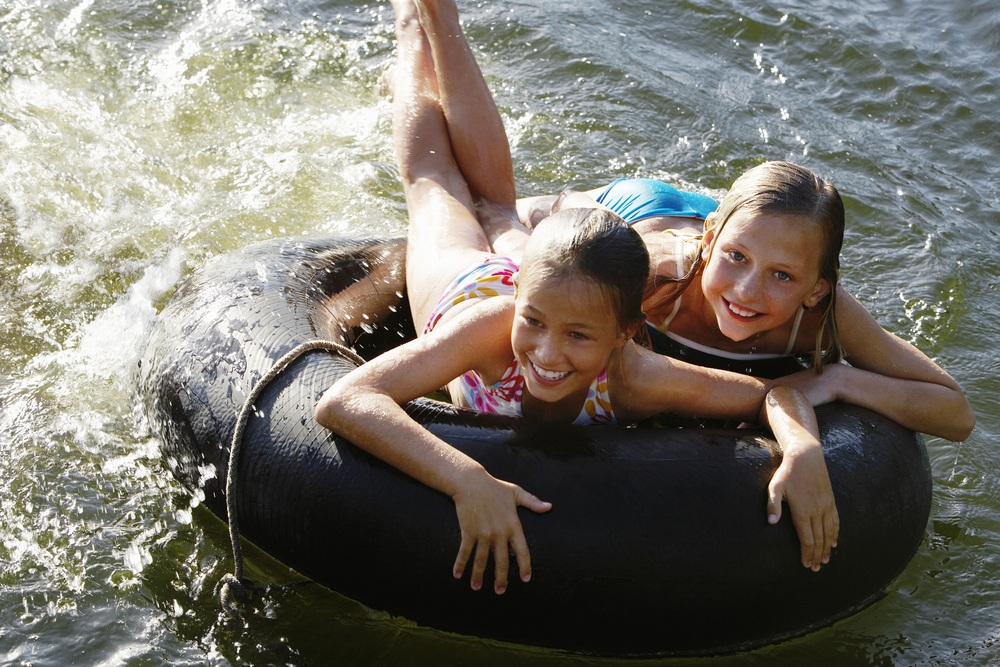 Happy young girls lying on float tube at lake