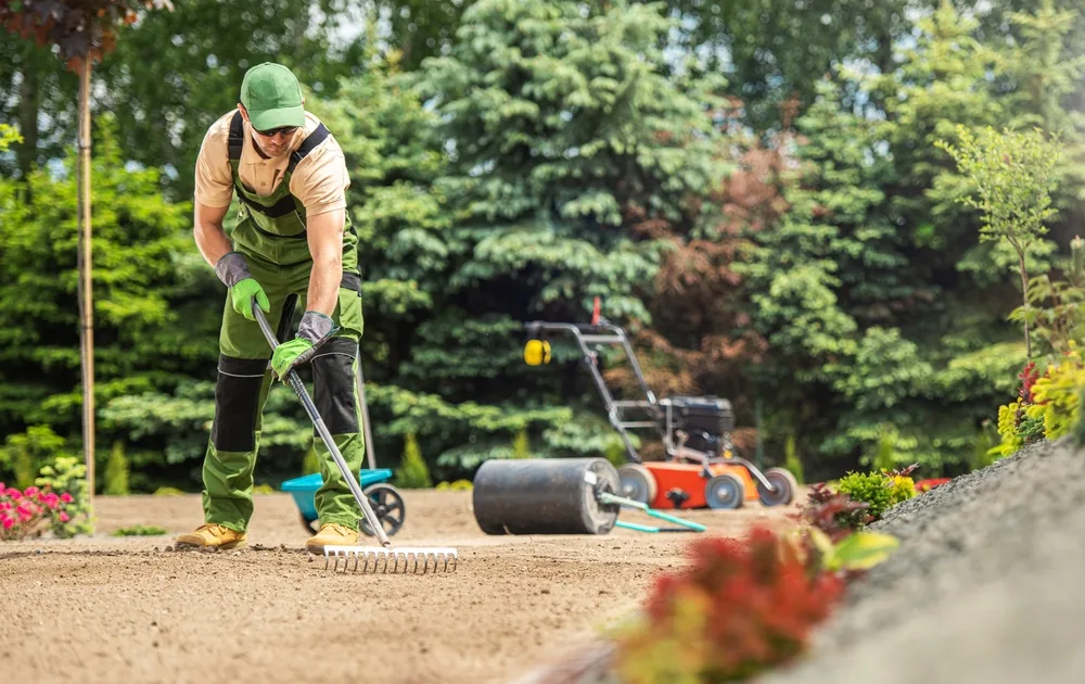 Garden Specialist with Rake Preparing Soil For Natural Grass during the Best Time to Plant Grass Seed in Minnesota