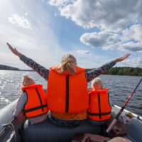 woman and two children on a boat with lifejackets on.