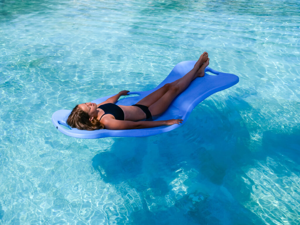 a woman floats on a best floating mat for lake.