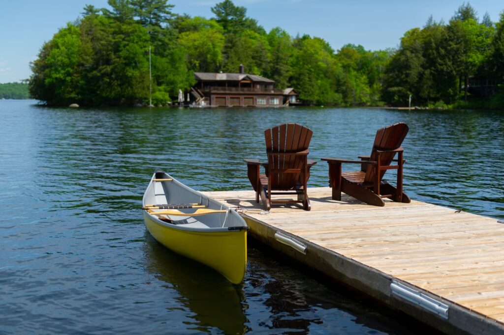 Adirondack chairs on a dock next to a yellow kayak.