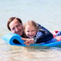 a father and daughter on a water mat.