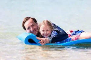 a father and daughter on a water mat.