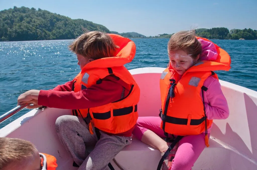 Kids wearing life jackets on a boat.
