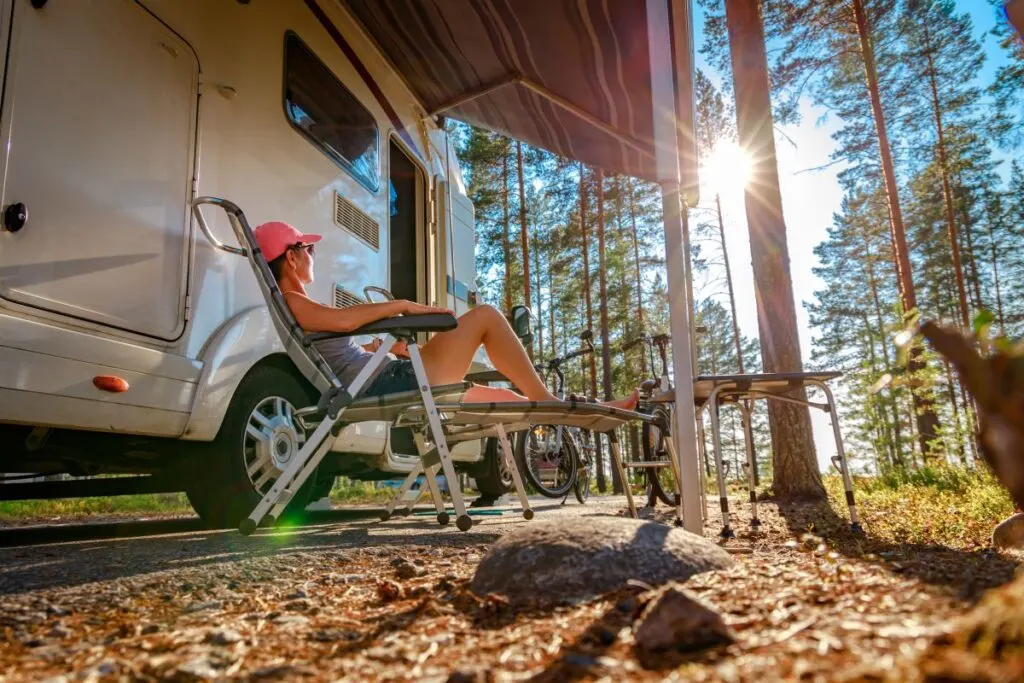 A lady sitting by an RV.