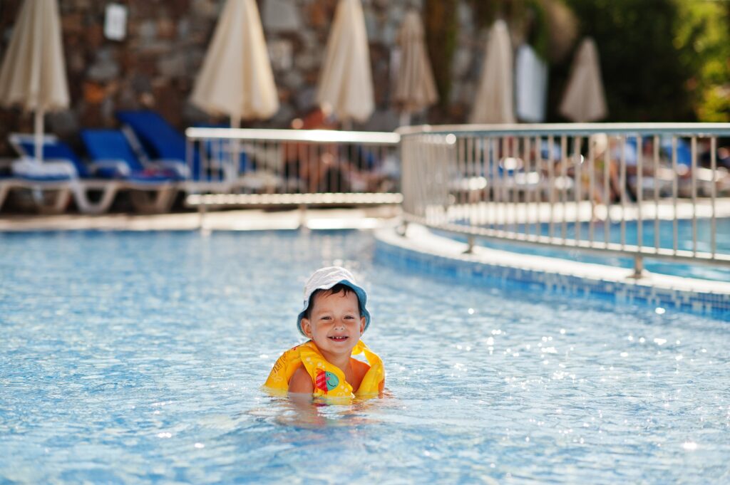 Toddler in pool with life jacket.