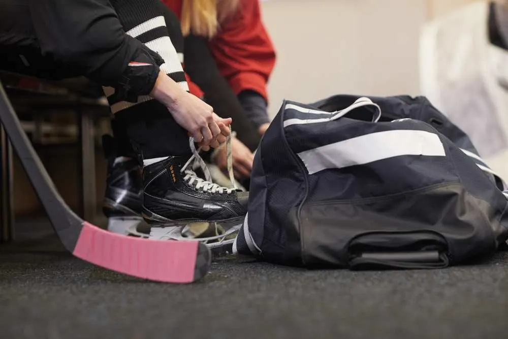 Lacing up hockey skates in preparation for skating on synthetic ice.