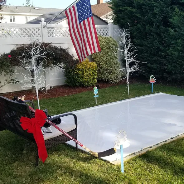 Synthetic ice rink set up in a backyard with an American flag.