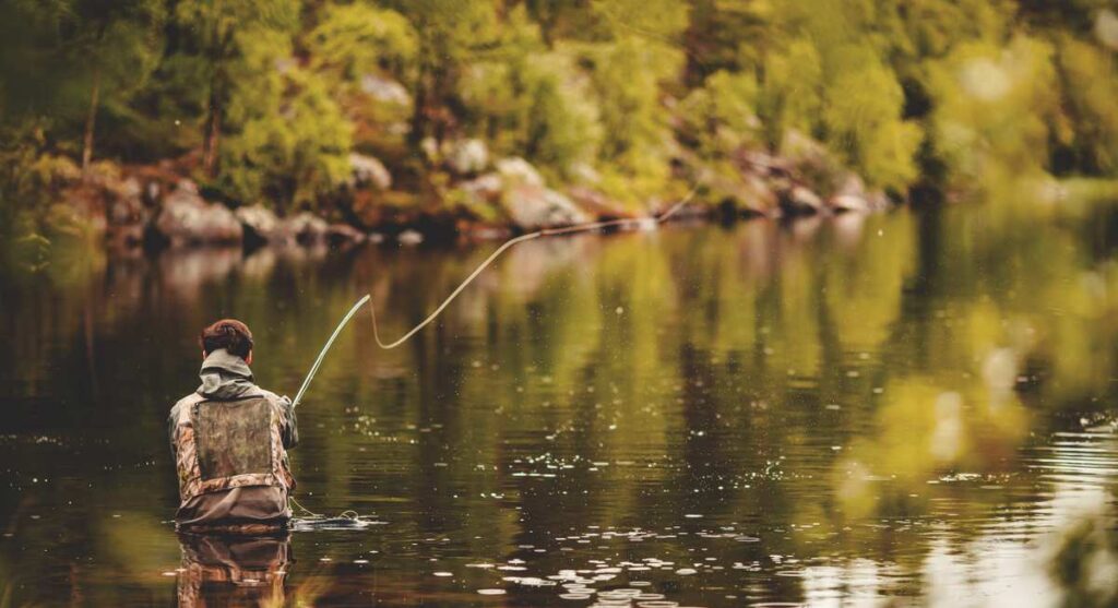 Fisherman using rod fly fishing in river.