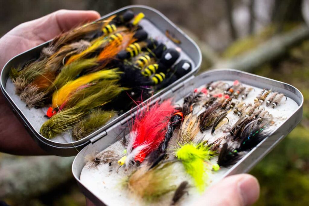 Man holding an open box of fishing flies.