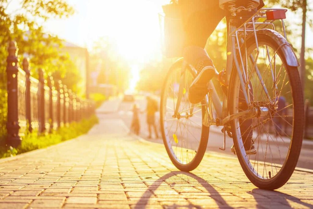 Person riding a bike in an urban setting on a sunny day.