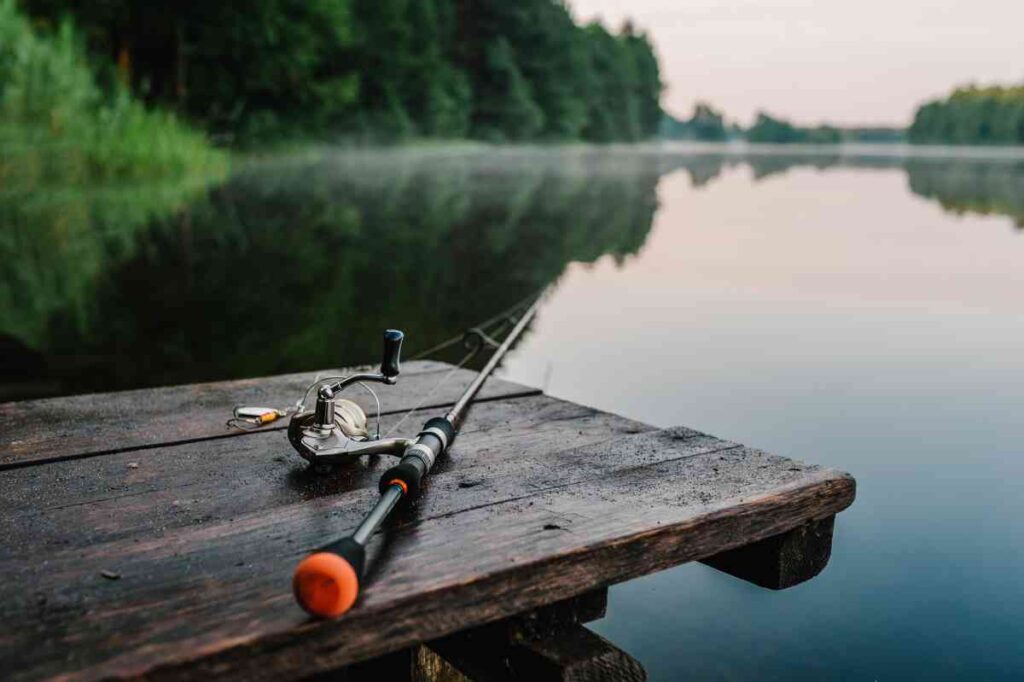 Fishing rod and reel on a dock at the edge of lake ready to catch freshwater fishing species