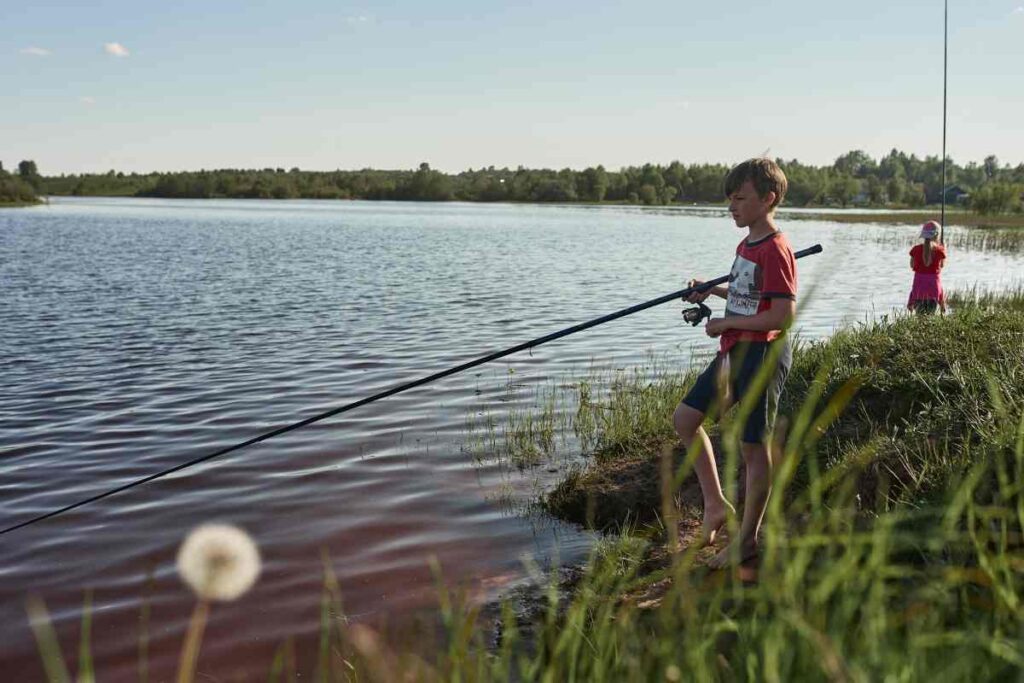 Children fishing by a lakeshore