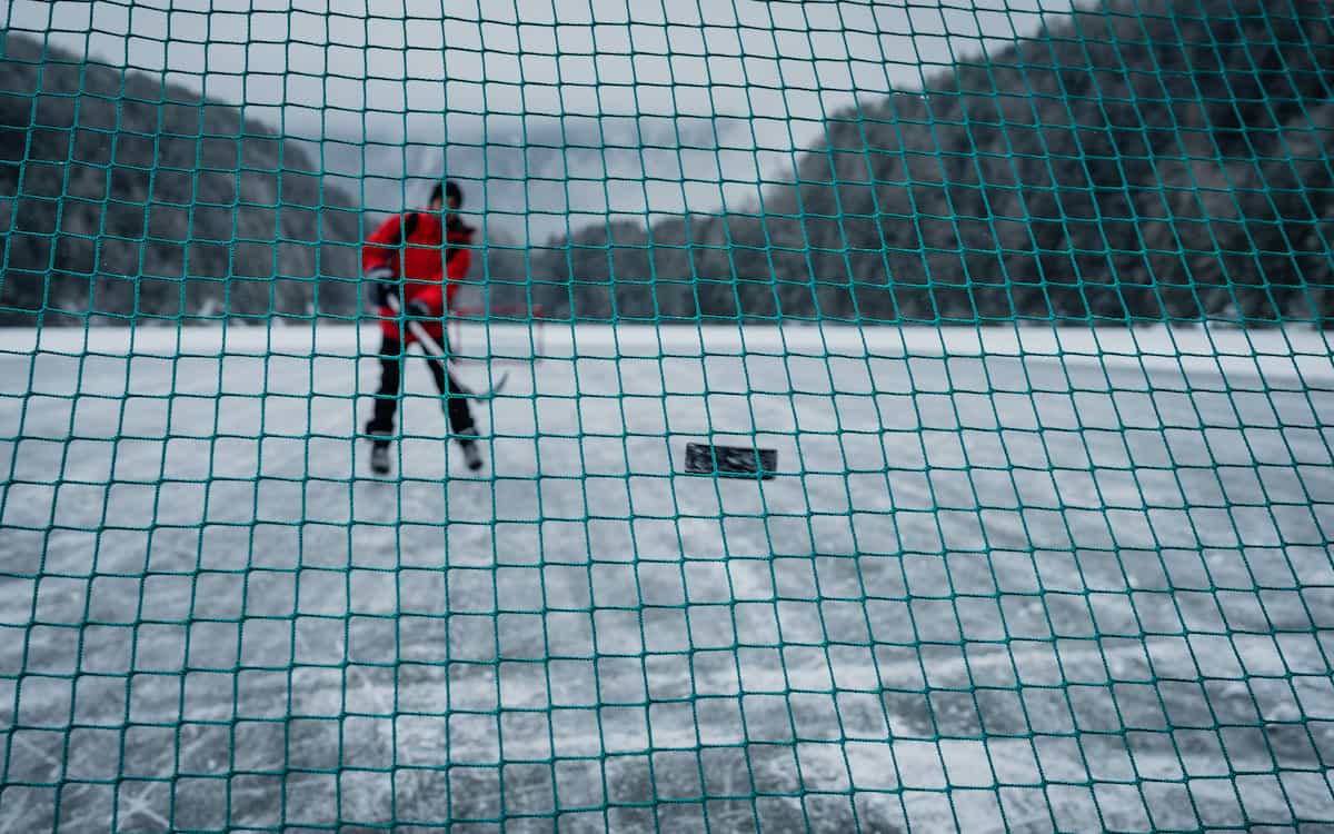 Lone ice hockey player on ice outdoors.